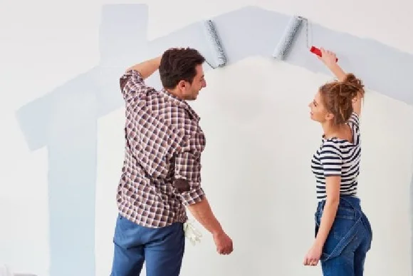 Zwei Personen streichen eine Wand mit Farbrollern.